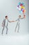 man holding hand of woman jumping in air with bundle of colorful balloons