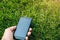 Man holding in hands broken smartphone lying in the green grass lawn outdoors. Damaged screen from the accidental fall. Modern