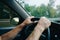 Man is holding hands on the car`s steering wheel. Raindrops on the windscreen. Guy is traveling in the bad weather. Dangerous