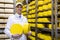 Man holding a head of cheese at a dairy plant