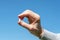 A man holding in his hand pill on the blue sky background. The cure for viruses, bacteria, allergies. Creative.