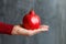 Man holding in his hand a ripe big red pomegranate, black stone background