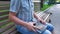 Man is holding Holy Bible in his hand sitting on a bench in a park in the summer on a sunny day