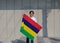 The man holding Mauritius flag in his hands on grey background