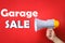 Man holding megaphone and phrase GARAGE SALE on red background