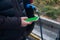 Man holding a mobile phone with green screen near the charged electric car