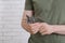 Man holding multitool near white brick wall, closeup