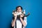 Man holding near face lying on back cute gray and white cat and looking at camera in front of blue background