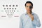 Man holding ocluder with eye vision examination chart