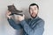 Man holding an old leather boot with torn sole, surprise and shock on his face