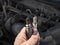 Man Holding old and new car spark plugs on engine background