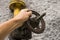 Man holding old weathered gas crane on the background of a gray wall. Old gas gate of yellow colour is on a pipe and