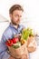 Man holding paper grocery shopping bags in the kitchen