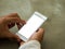 Man holding phone left hand using smartphone pointing finger on white screen on top view