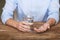 Man holding pills and glass of water at wooden table, closeup