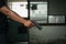 Man holding a pistol, standing in a room in black, pointing and aiming a gun at a target. concept of assassination, murder,