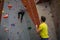 Man holding rope looking at athlete climbing wall in fitness studio