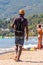 Man holding showing offering selling various printed books while walking on the beach between resting tourists