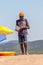 Man holding showing offering selling various printed books while walking on the beach between resting tourists