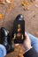 Man holding smartphone with Happy Thanksgiving photo message on the screen outdoors in park full of autumn leaves on the ground