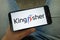 Man holding smartphone with Kingfisher plc British retailing company logo