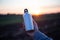 Man holding a steel bottle on the background of sunset