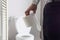 Man holding tissue paper standing next to toilet bowl