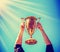 A man holding up a gold trophy cup as a winner in a competition