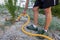 Man holding a water hose and watering a newly plated small tree in the street