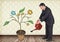 Man holding watering can and Drawing of Business graphics on plant branches on wall