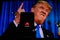 A man holds an android-smartphone that shows the logo for the google play store in front of the picture of Donald Trump
