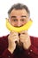 Man holds banana to face, imitating smile