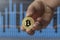 man holds a bitcoin coin in his hand. bitcoin growth chart