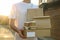 Man holds blank box, coffee cups and package outdoor. Delivery