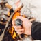 A man holds a compass by the burning bonfire in winter. Concept hike, walk, journey