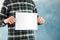 Man holds empty sheet on blue background