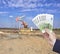 A man holds euro money in his hand against the background of a well that produces oil and gas. The concept of the oil economy and