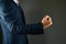 A man holds a fist in front. A man in a suit shows a kuak forward on a black background. Concept: strength in business