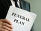 Man holds Funeral plan and stack of papers