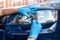 man holds a halogen bulb in his hand against the background of washed car headlights.