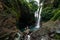 A man holds the hand of a beautiful woman at a waterfall. A couple in love on a waterfall. Honeymoon trip. Happy couple