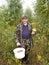 The man holds in hand a bucket with mushrooms in the wood