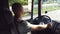 Man holds hand on the steering wheel and driving truck through countryside on a warm summer day. Profile of truck driver