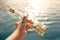 Man holds in his hand a bottle with message on the background of the sea