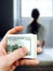 Man holds in his hand a bundle of one hundred dollar bills against the background of the girl who they are going to sell into slav