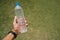 man holds in his hand an empty plastic bottle on a background of green grass. Plastic problem and failure