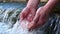 A man holds his hand washes his hands in the fountain water, clearing them of dirt, and holding the water of the waterfall in