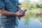 A man holds in his hands a caught catfish with a hook in his mouth in a pond, on in the park