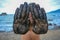 Man holds his hands in front of camera. Black sand covers the hands, blue sea in background. Closeup of two black hands