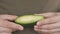 A man holds in his hands a half ripe avocado fruit